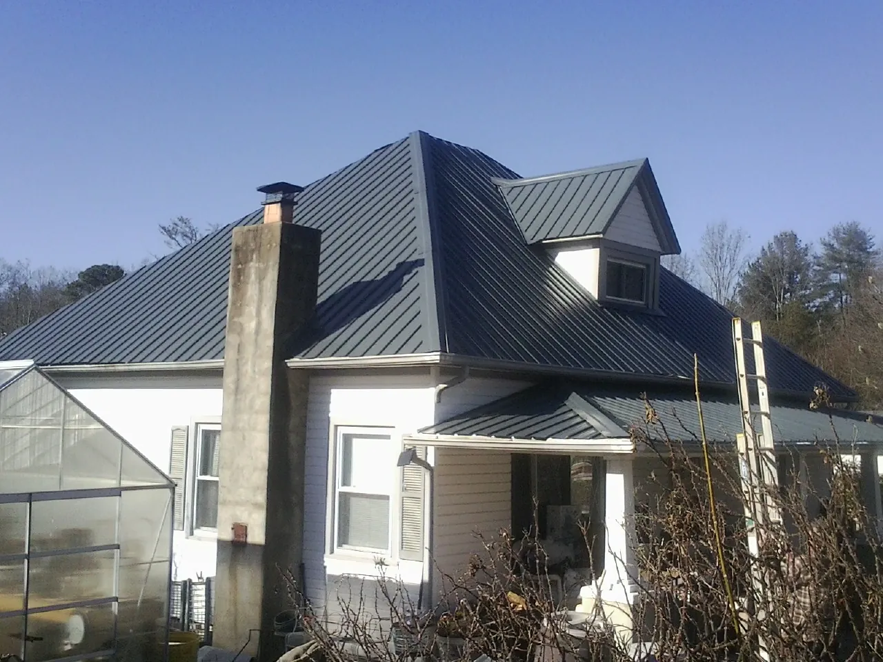 Dark blue standing seam metal roof on a white farmhouse with dormer — Slate & Tile Roof Repair by Roofing Brothers in Leitchfield