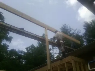 Carpenter setting a ridge beam over a new addition frame in Leitchfield