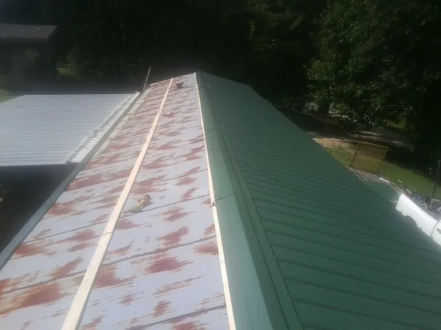 Old rusted panels beside newly installed green metal roofing — Wind Damage Roof Repair by Roofing Brothers in Leitchfield