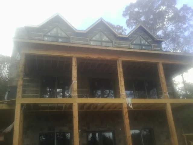 Dormers and porch framing on a large log home under construction — Roof Coating work by our crew in Leitchfield