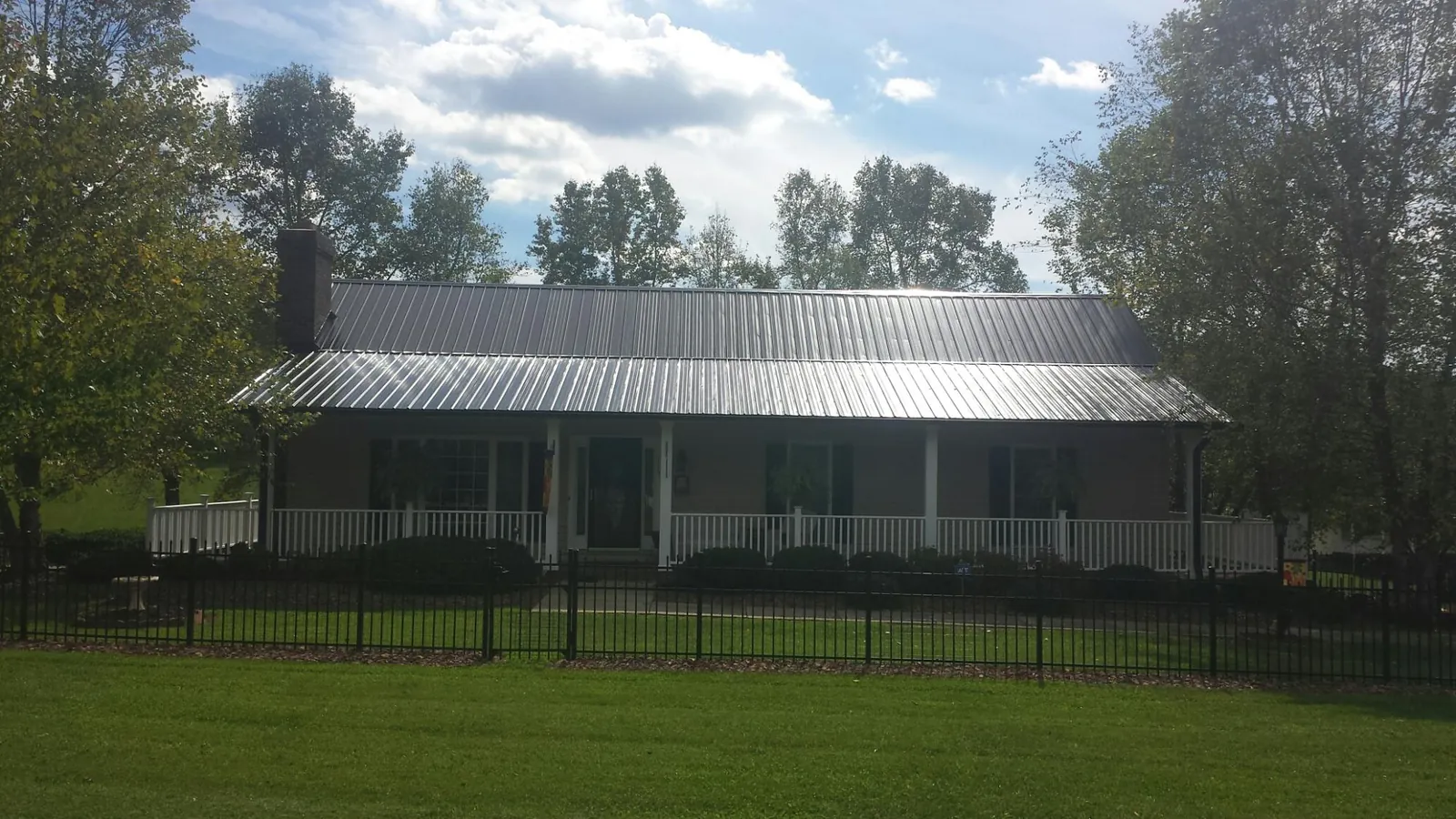 Gray metal roof on a brick ranch with a full width front porch — Gutter Guard Installation work by our crew in Leitchfield
