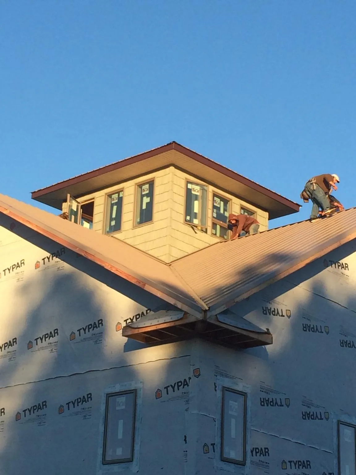 Roofers working around a rooftop cupola on a new metal roof at sunset — Roof Waterproofing in Leitchfield by Roofing Brothers